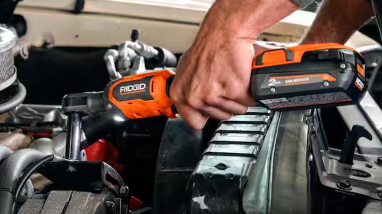 A person using a Ridgid ratchet on a vehicle.