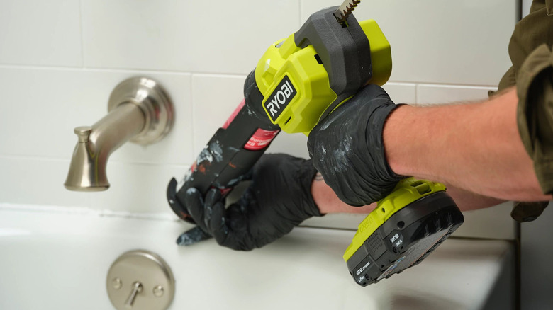 person using ryobi caulking gun
