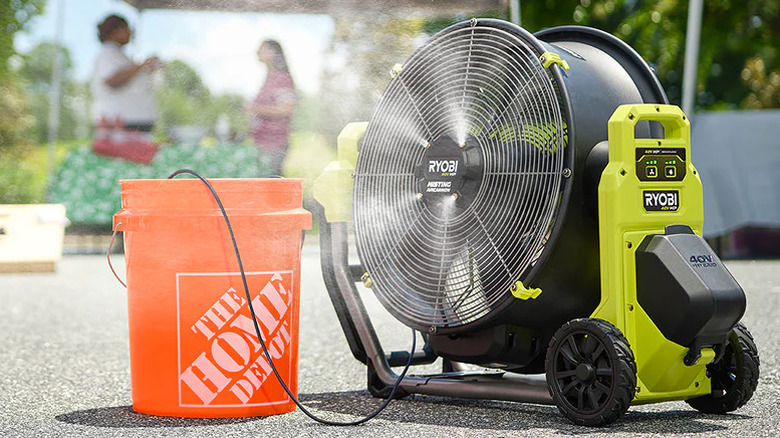 A Ryobi 40V HP Brushless Hybrid 18-inch Misting Air Cannon running outside using water from a Home Depot bucket..
