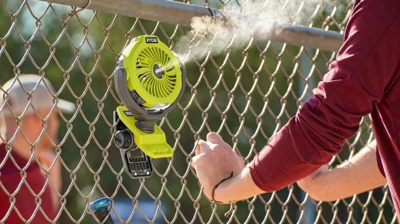 A small Ryobi USB misting fan clipped to a fence.