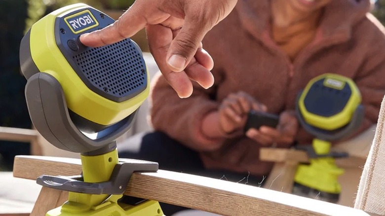 Person pressing the power button on a Ryobi Clamp Speaker