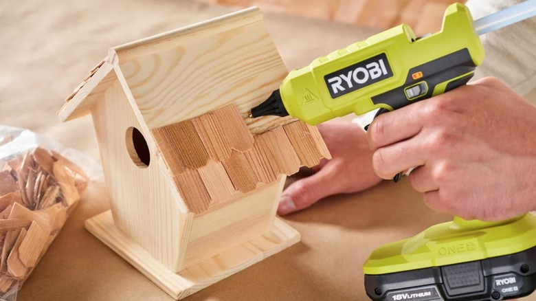Person using Ryobi glue gun to make a bird house