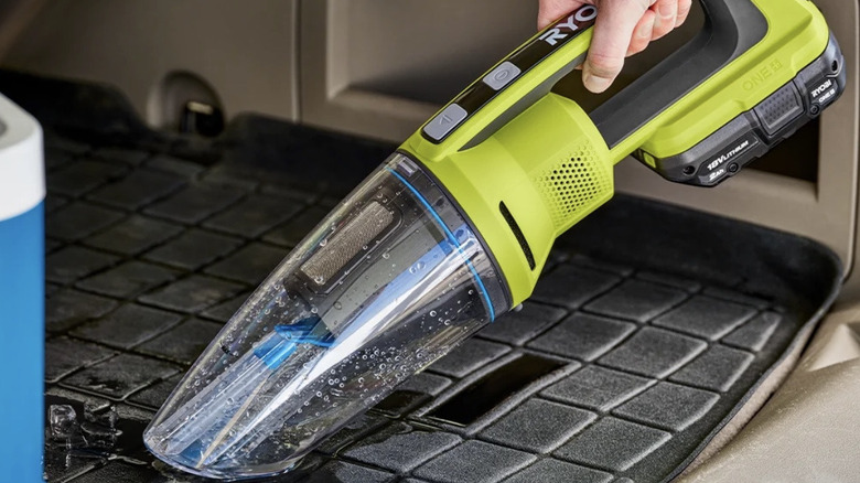 Person using a Ryobi wet/dry vac to clean up a mess in a car