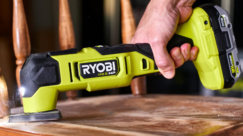 Person sanding using a Ryobi oscillating multi-tool