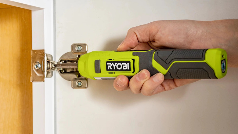 Person using a Ryobi FVD01K cordless screwdriver to fasten a cabinet door hinge