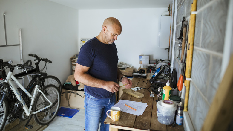 A man taking measurements in a workshop.