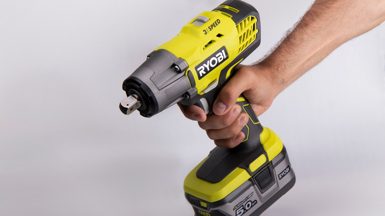A person holding a yellow cordless Ryobi tool.