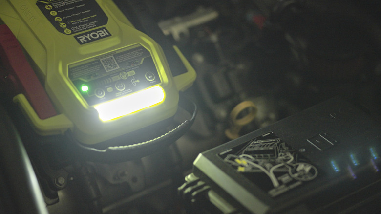 person jump starting car with ryobi jump starter