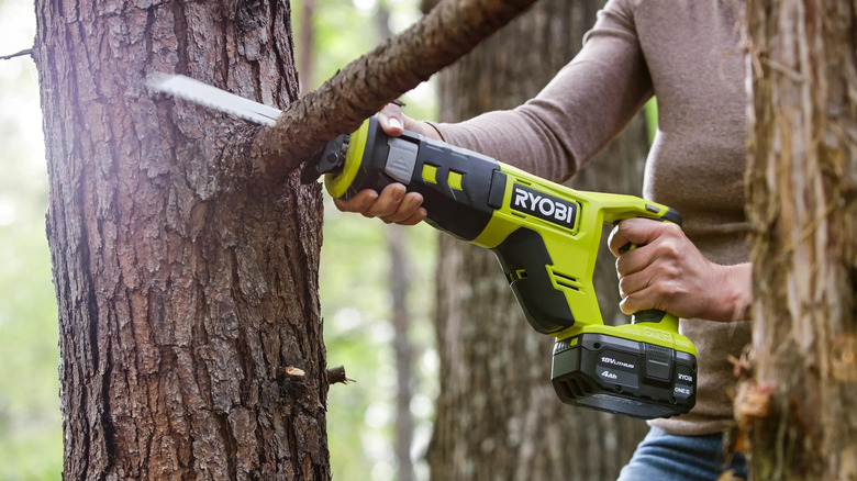 Ryobi PCL515B reciprocating saw cutting a branch