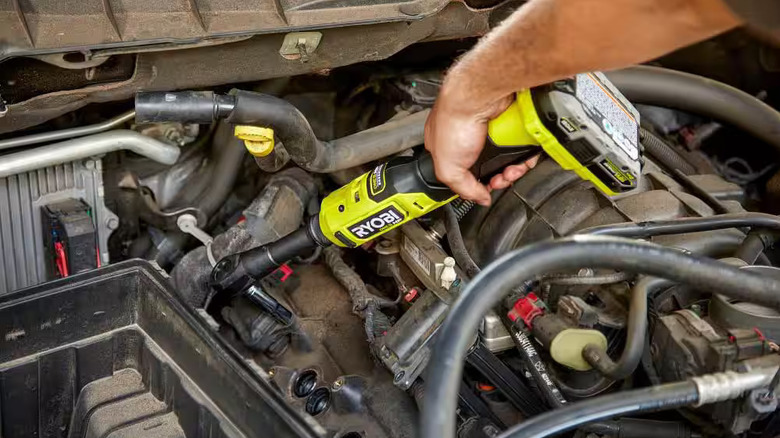 Working on a car engine with a Ryobi extended reach ratchet