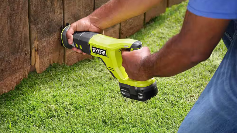 Ryobi reciprocating saw cutting a hole in a fence