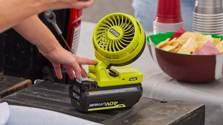 A person using a Ryobi cordless fan outside.