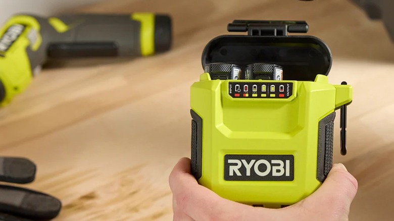 A person holding the Ryobi USB Lithium 3-Port Charger and Power Source.
