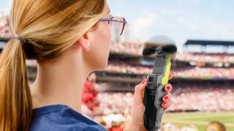 A woman using the Ryobi USB Lithium Cordless Handheld Portable Fan at a sporting event.