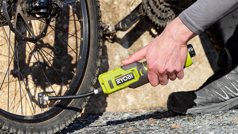 A person inflating bike tire with Ryobi inflator