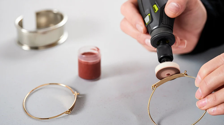 A person polishing jewelry with Ryobi rotary tool