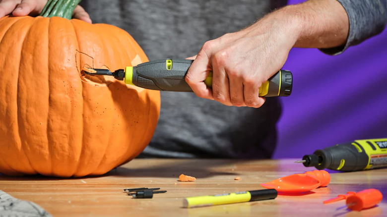 Person carving a pumpkin with Ryobi tools