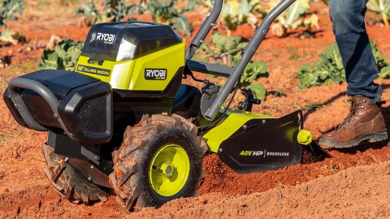 Boot steps being 40V HP Brushless 18-inch Rear Tine Tiller while tilling soil