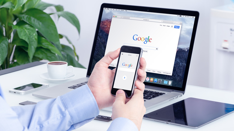 man browsing the web on an iPhone and Mac