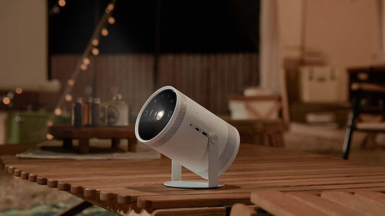 A white Samsung portable smart projector on a deck.