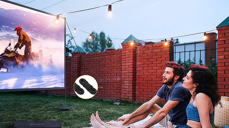 A projector screen in a garden with two people watching it.