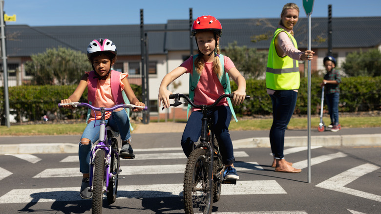 Children on bicycles riding through a crosswalk.