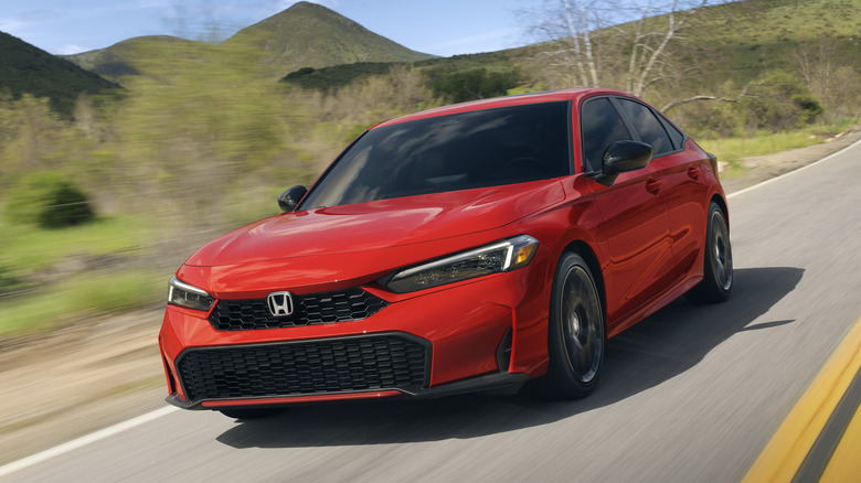 Front 3/4 view of red Honda Civic Hybrid sedan on mountain road.