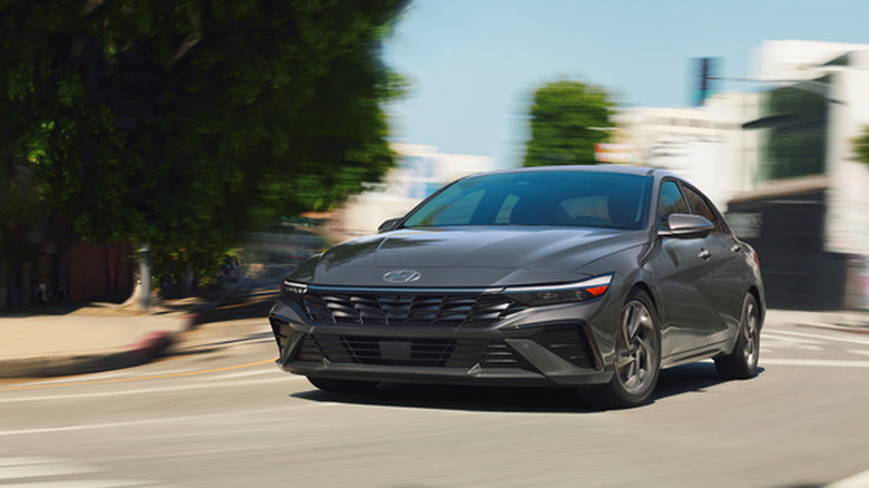 Front view of gray Hyundai Elantra Hybrid driving on city street.