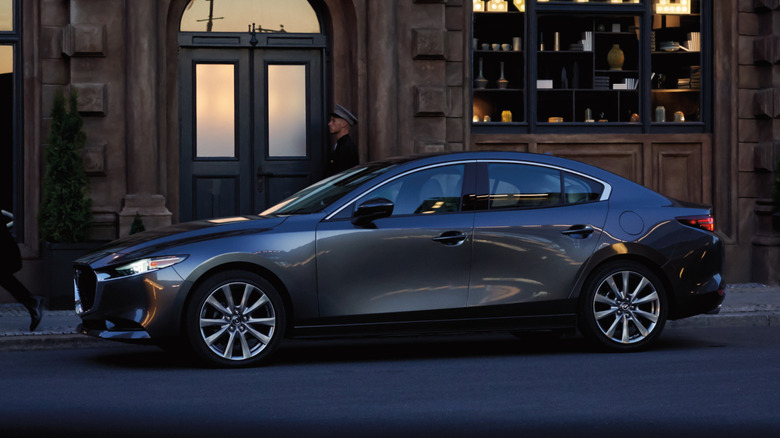Side view of gray Mazda3 sedan parked on urban street.
