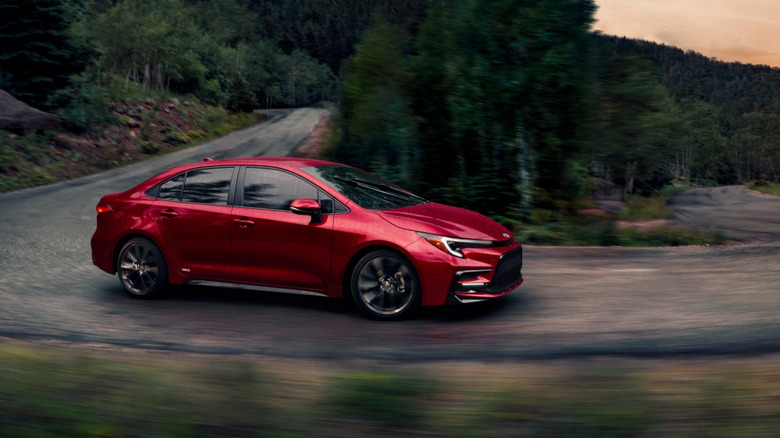 Side view of red Toyota Corolla Hybrid driving on mountain road.