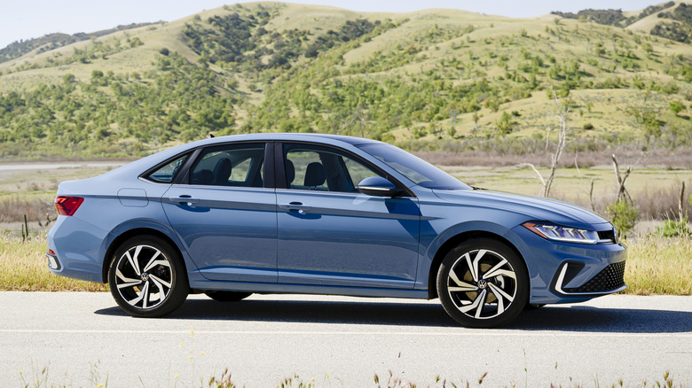 Side view of gray Volkswagen Jetta sedan parked in front of foothills.