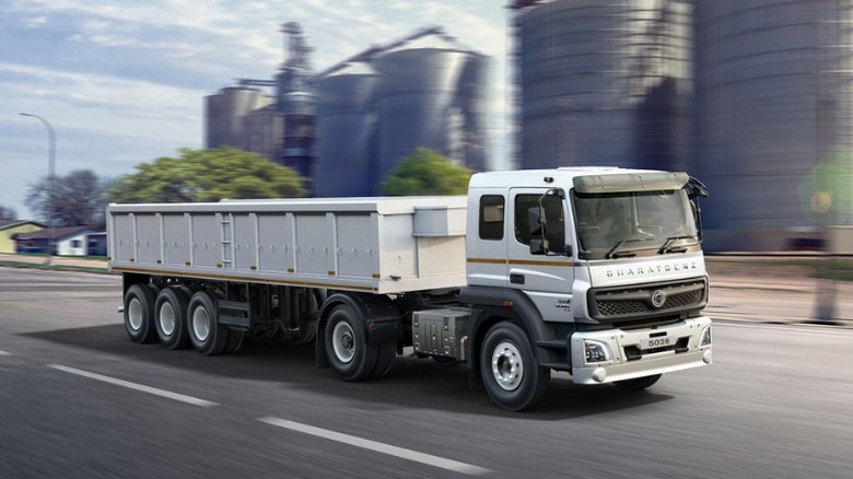 A white BharatBenz semi driving past industrial buildings