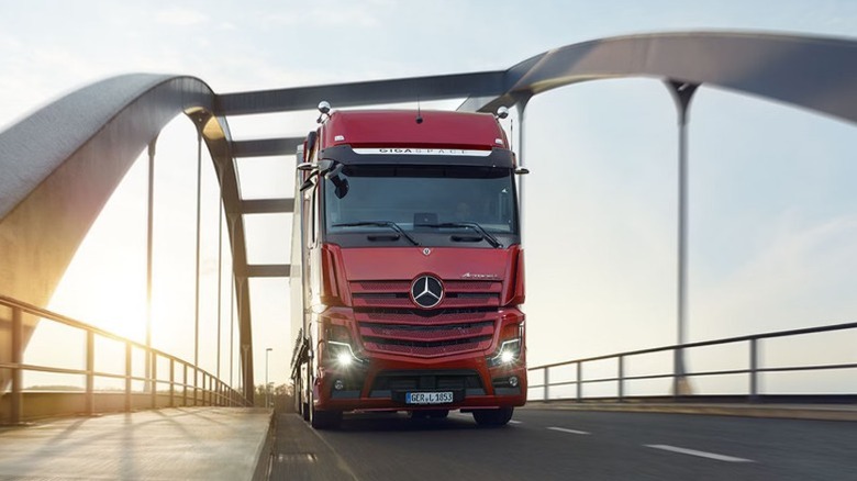 A red Mercedes-Benz Actros L driving across a bridge