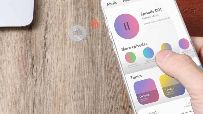 An NFC tag stuck on a table being scanned by a smartphone