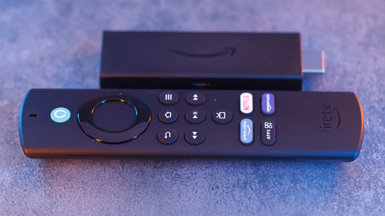 Close up picture of an Amazon Fire TV Stick next to a Fire TV remote