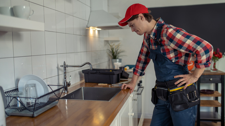 Plumber looking confused while inspecting a kitchen sink