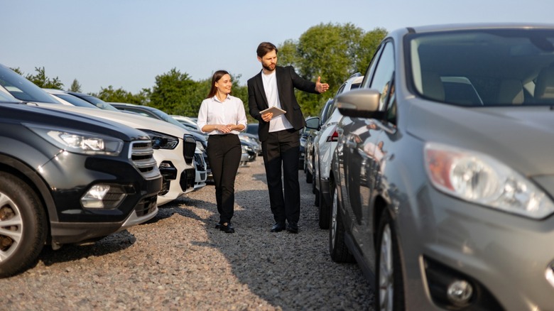 Two people looking at cars in a parking lot