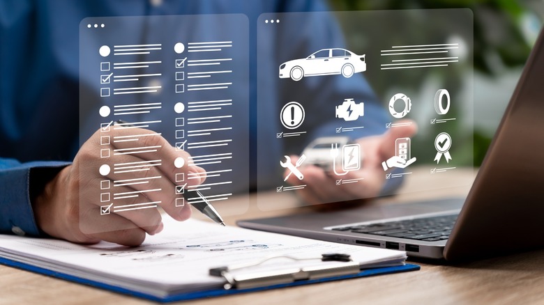 A holographic overlay of vehicle issues superimposed over a person using a clipboard and laptop