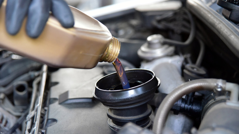 Person adding oil to an automobile's engine