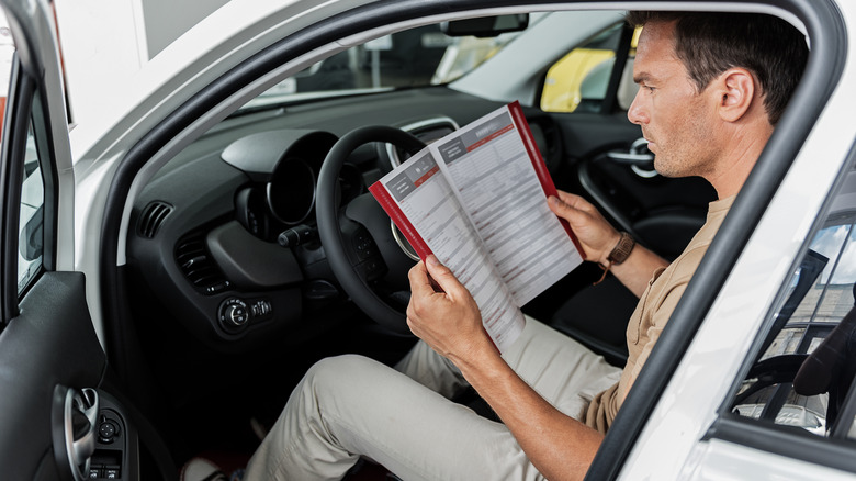 Person reading their car's owner's manual