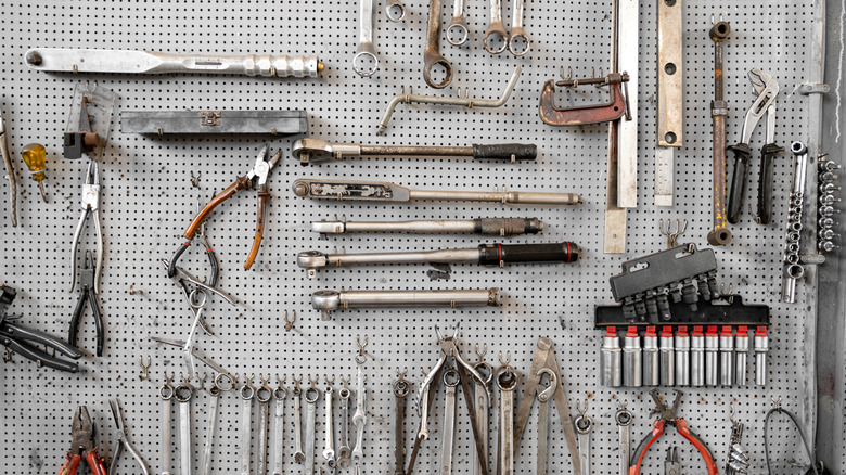 A selection of tools on a pegboard in a workshop.