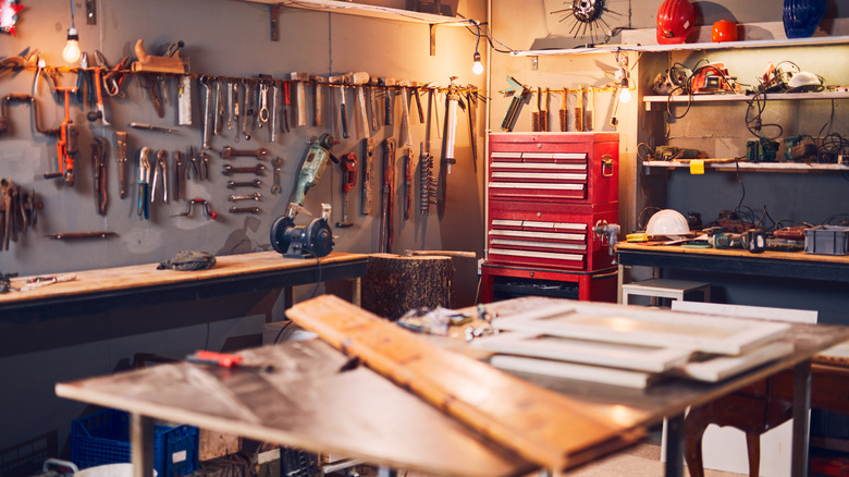 A workshop with lots of tools on the wall and shelves.