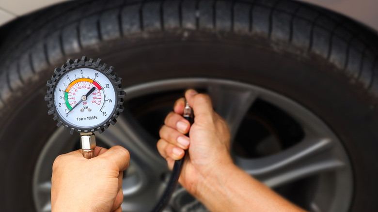 Person checking their tire pressure with a gauge