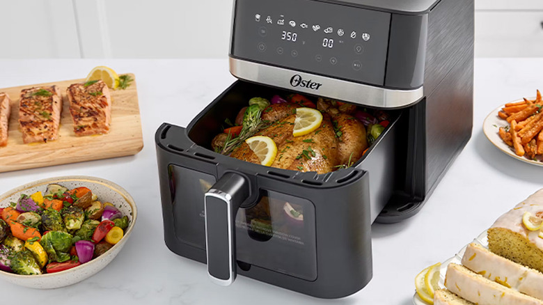 An Oster air fryer with a bunch of food in and around it.