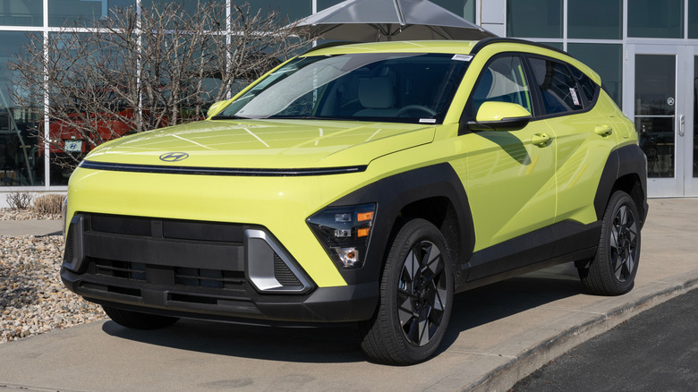 A yellow Hyundai Kona parked in front of a dealership.