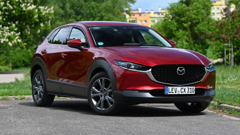 A red Mazda CX-30 parked in a city street.
