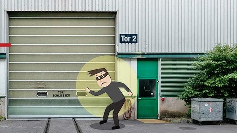 A cartoon burglar grabbing about to grab a garage door, but is caught by a light.