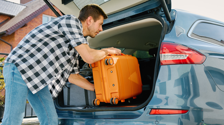 Man putting a suitcase into a tidy, organized car