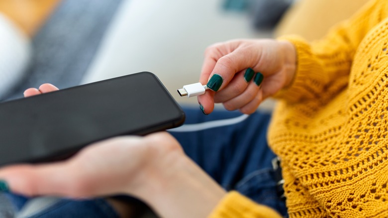 Woman plugging in smartphone to charge