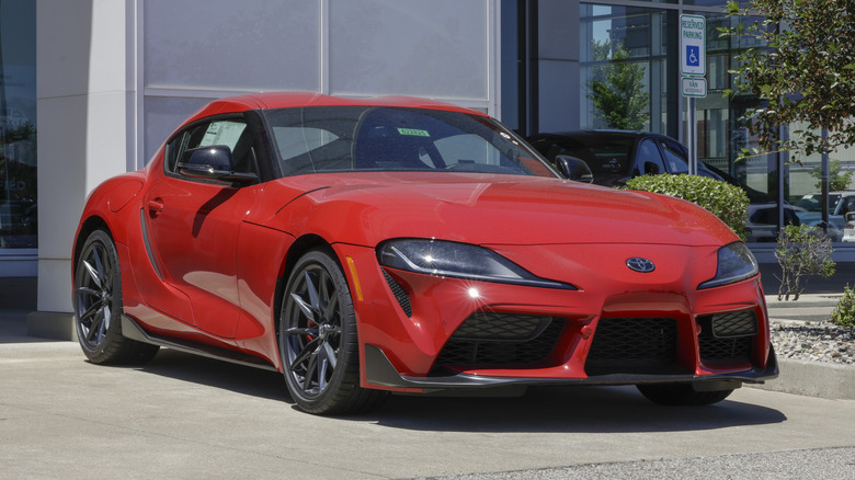 A red A90 Toyota Supra parked outside a dealership.